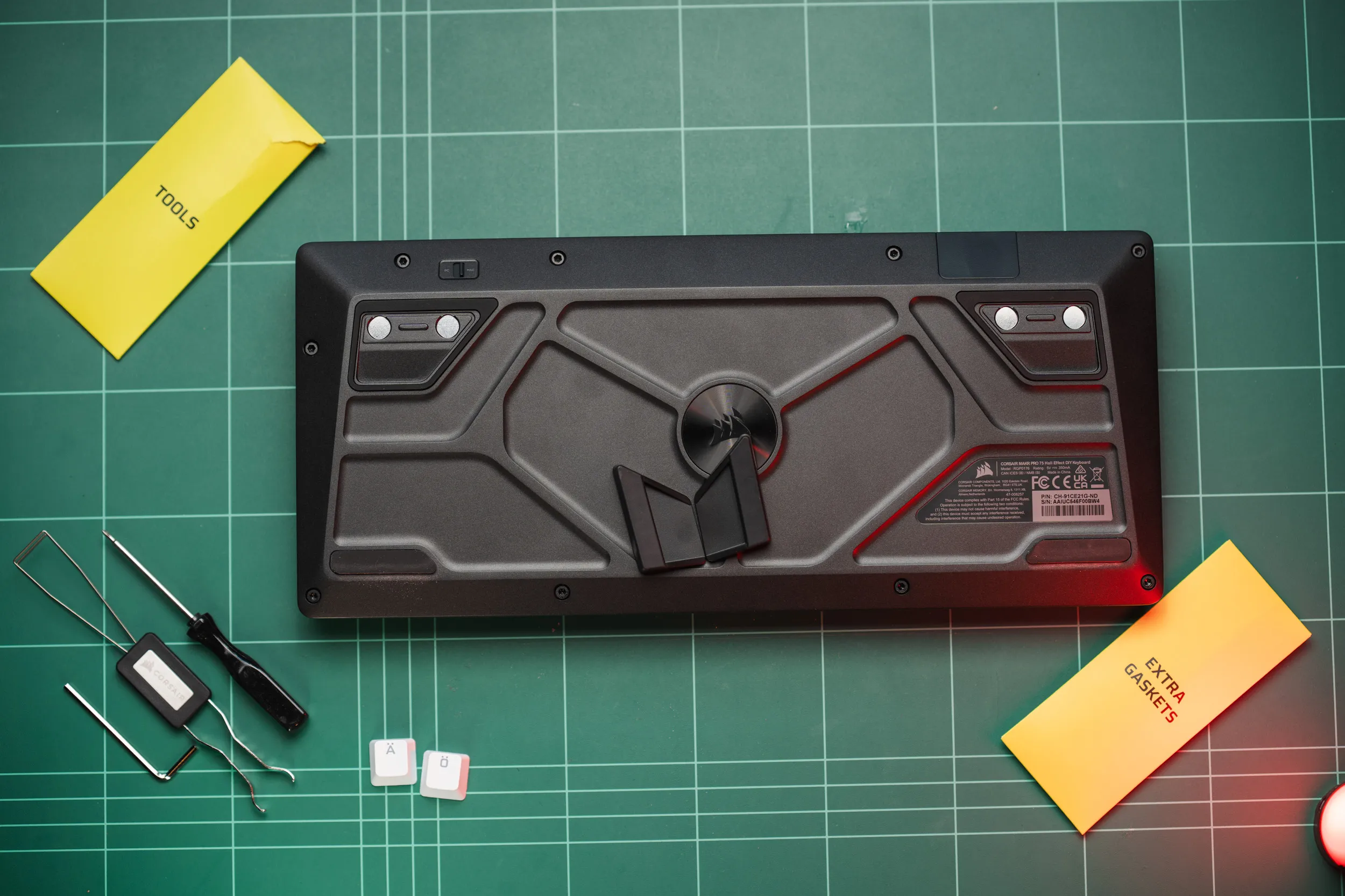 The underside of the Corsair MAKR PRO 75 showing the sculpted base, the nine Torx screws, the magnetic feet and the PC/Mac switch