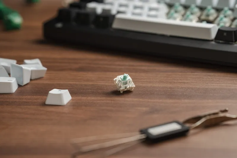 A single Corsair MGX Hyperdrive magnetic switch standing on a wooden desk next to spare keycaps