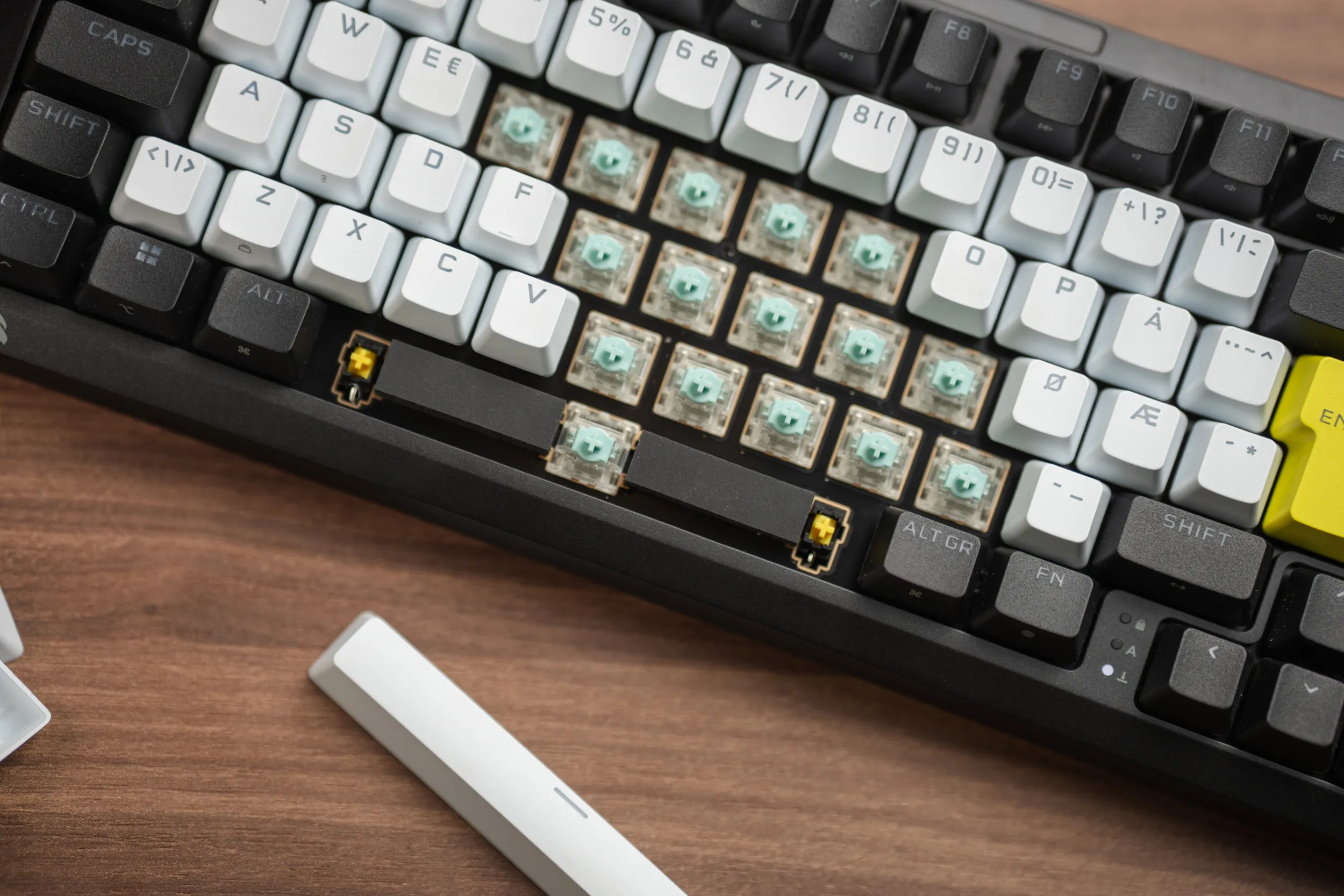 A block of keycaps removed from the Corsair MAKR PRO 75, showing the green MGX magnetic switches seated in the hot-swap sockets