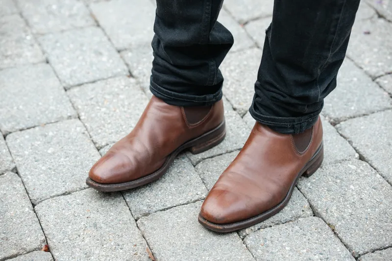 Brown R.M. Williams Comfort Craftsman worn with black jeans, top down on grey cobblestone