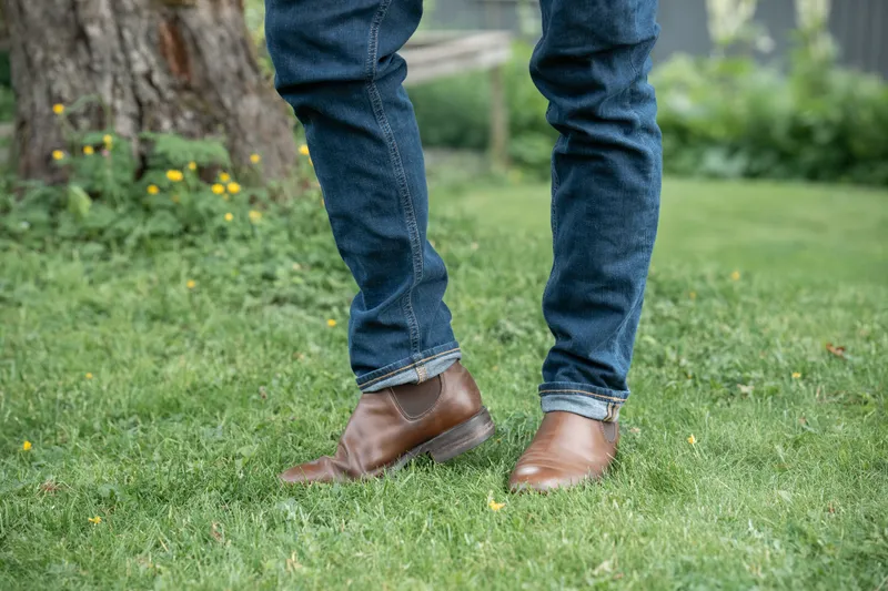 Brown R.M. Williams Comfort Craftsman worn with blue jeans, mid stride on grass