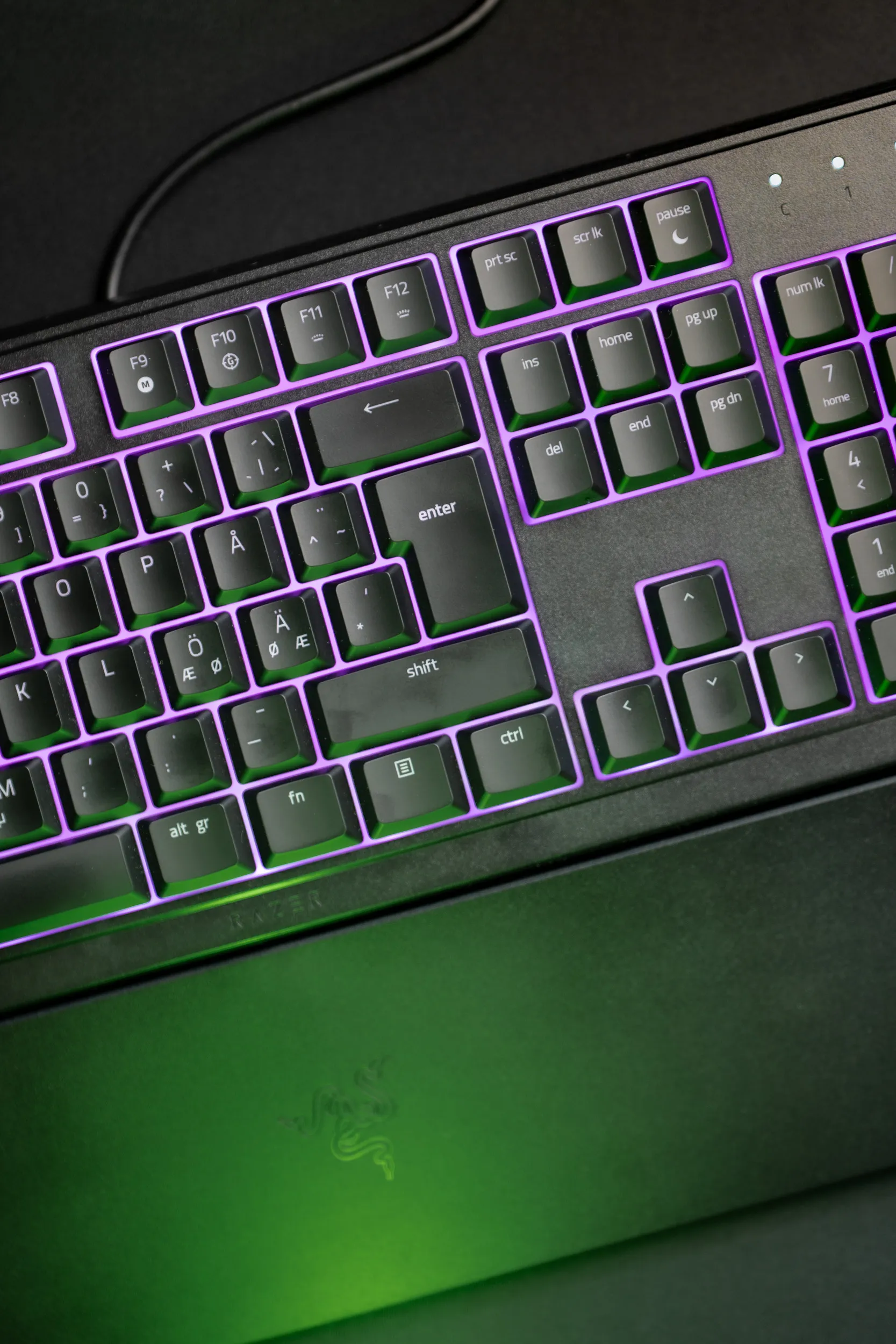 Close-up of the right side of the Razer Ornata V3 X with the keys lit in purple Chroma RGB and a green glow below