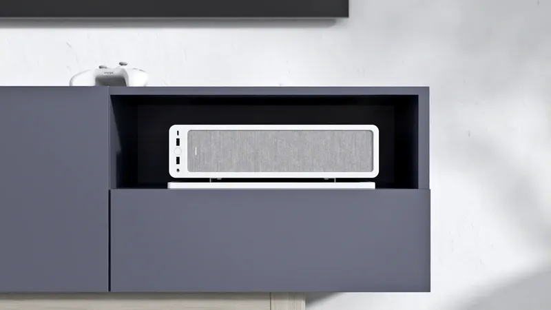 A white Fractal Ridge console-style PC sitting in a living-room media cabinet, a game controller resting on top