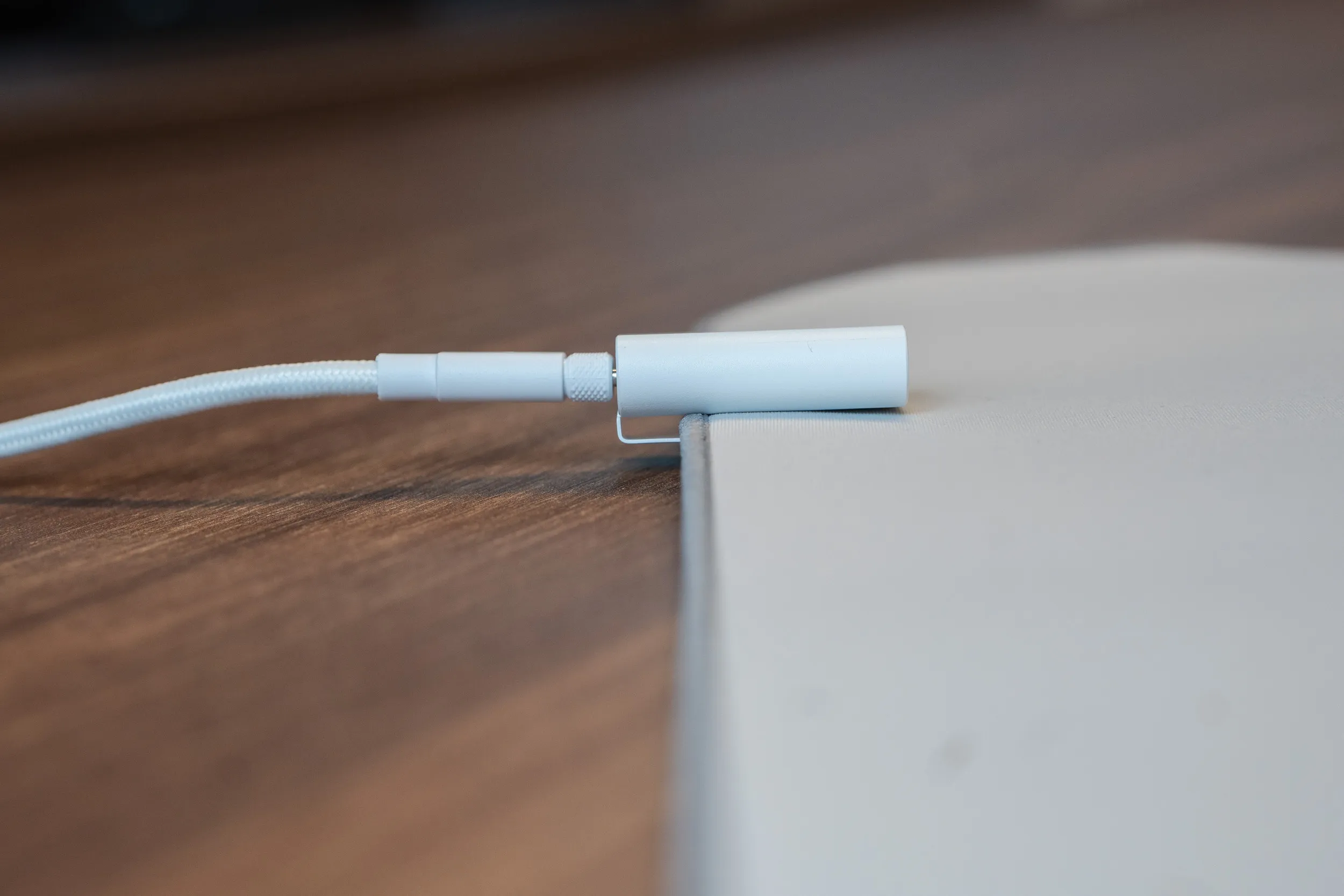 The white Sabre v3 Pro PureVector receiver on a braided cable, clipped onto the edge of a mousepad