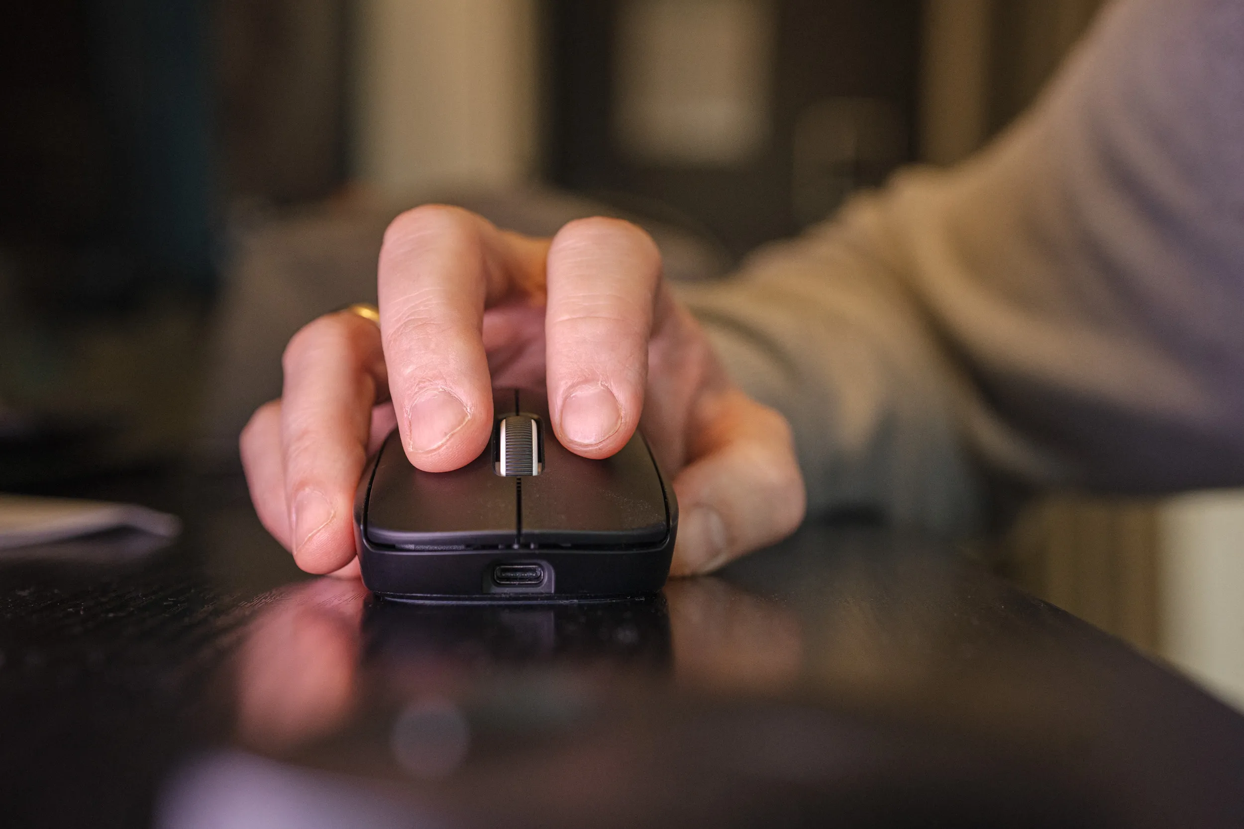 Hand holding the Logitech G Pro X Superlight 2, seen from the front with the USB-C port visible