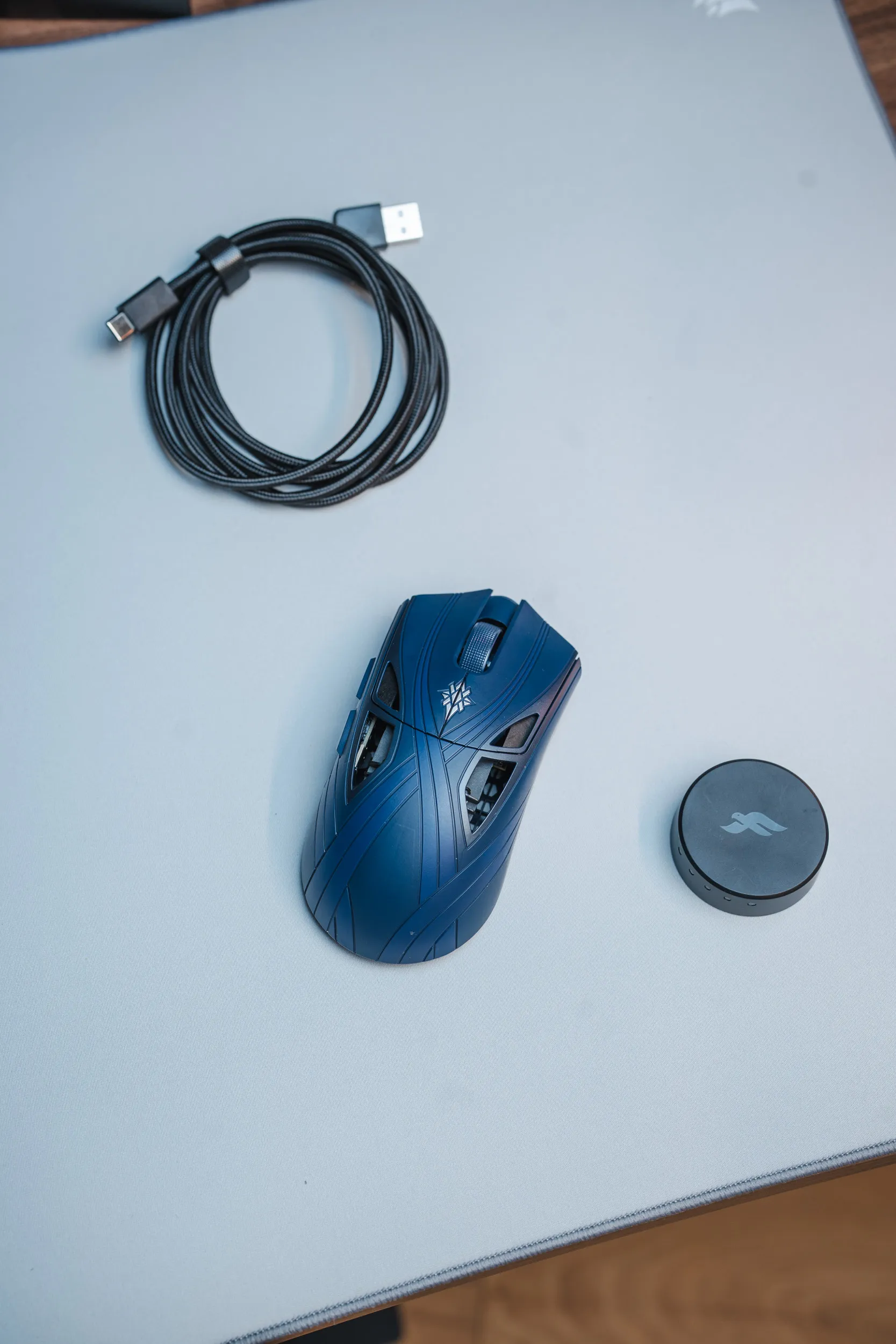 Finalmouse SLX Nightfall next to the round dongle and a braided USB-C cable