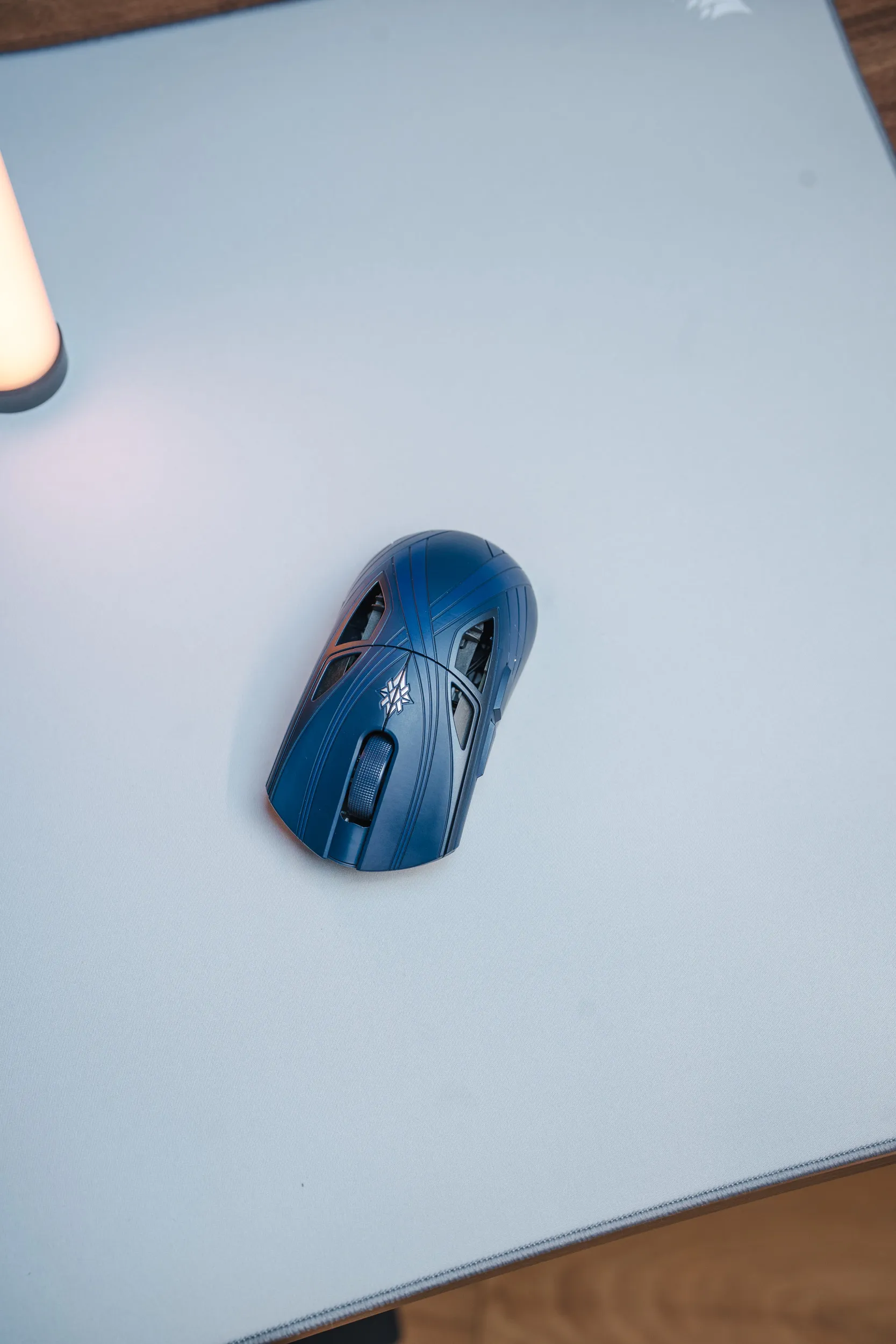 Finalmouse SLX Nightfall seen from above on a light mouse pad, with the symbol behind the scroll wheel and cutouts in the shell above both buttons