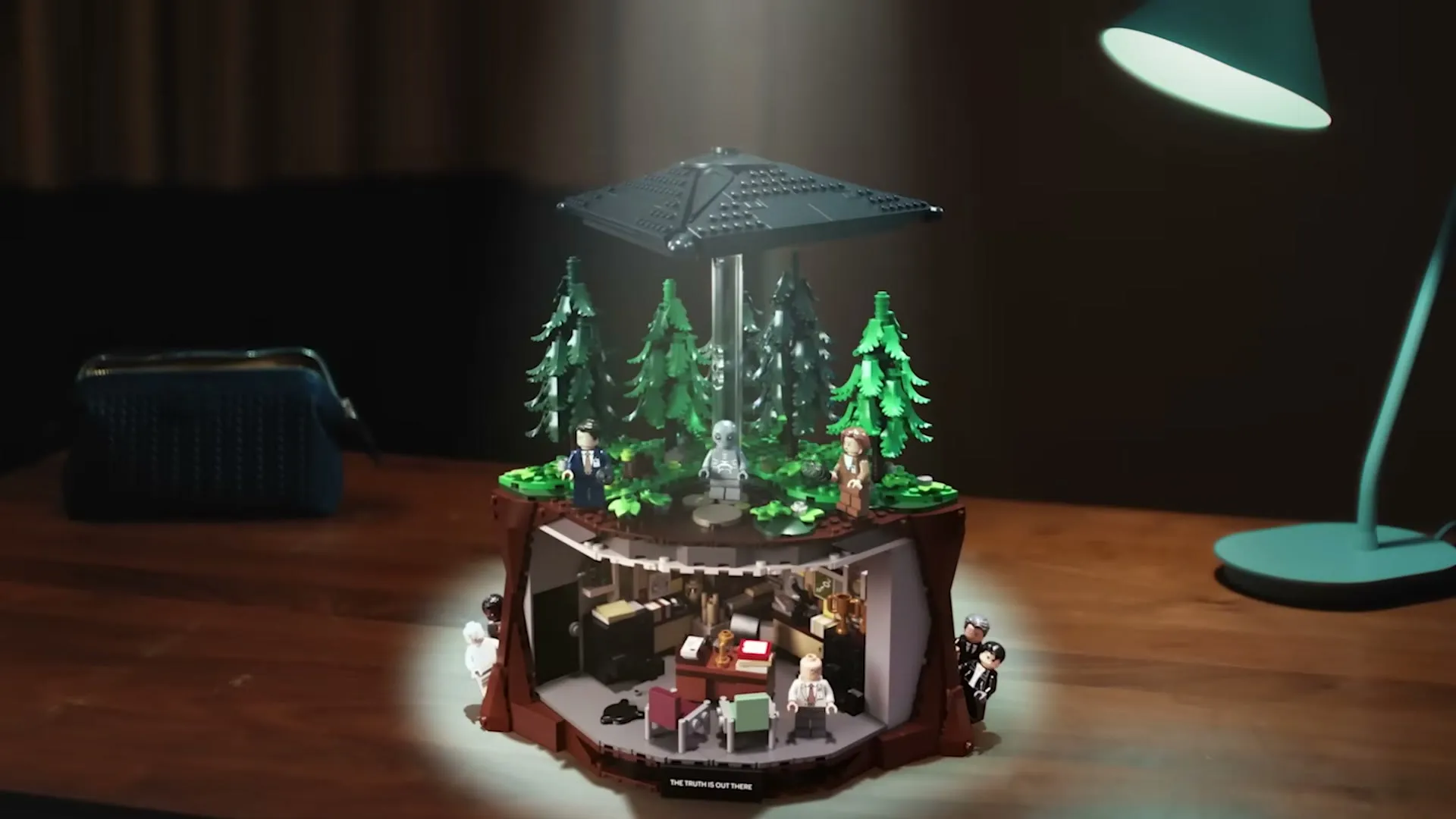 The finished LEGO X-Files set on a desk, with the office below and the UFO above the forest