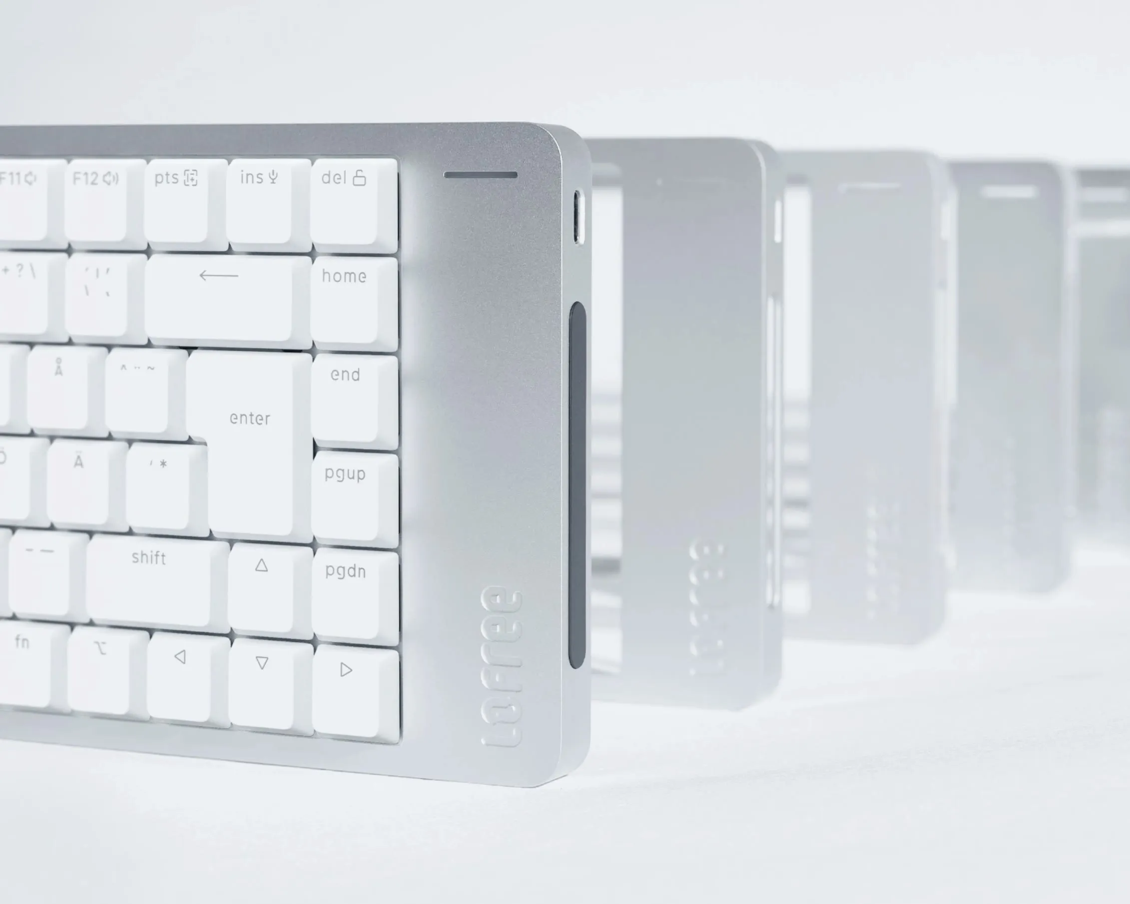 Lofree Flow 2 in white, close-up of the right corner with Nordic ISO layout and the touch bar on the short side, several keyboards lined up behind
