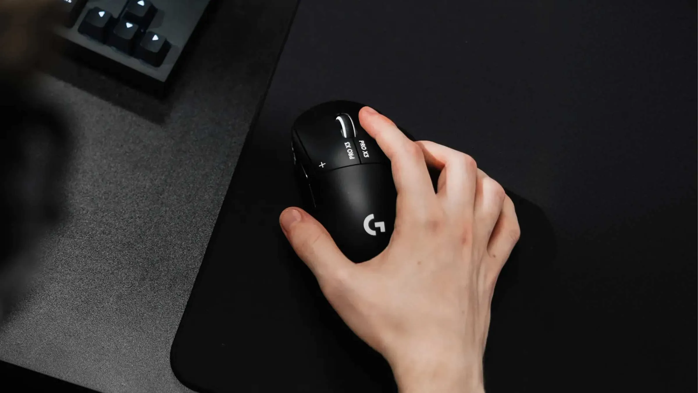Hand in a claw grip on the Logitech G Pro X3 Superstrike in Midnight Black on a dark mouse pad